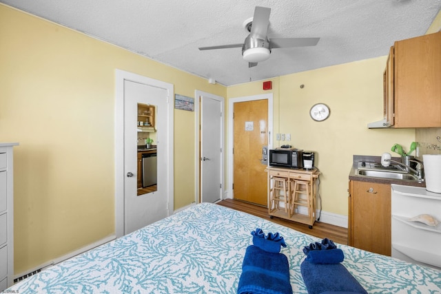 bedroom with sink, a textured ceiling, light hardwood / wood-style floors, and ceiling fan