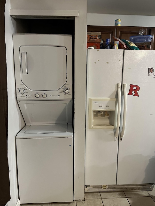 clothes washing area with light tile patterned floors and stacked washer and clothes dryer