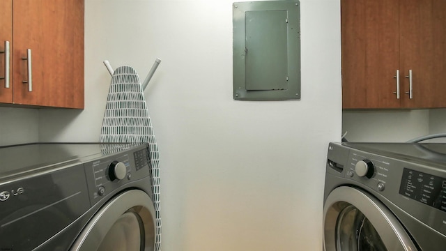 clothes washing area featuring cabinets, washing machine and dryer, and electric panel