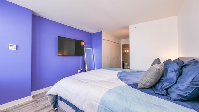 bedroom with light hardwood / wood-style floors and a closet