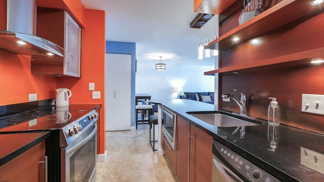 kitchen with stainless steel appliances, hanging light fixtures, sink, and wall chimney range hood