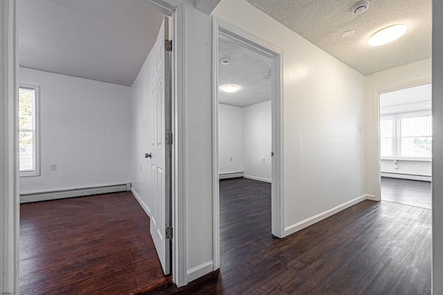 hall featuring dark hardwood / wood-style flooring, a wealth of natural light, a textured ceiling, and baseboard heating