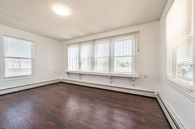 empty room featuring dark wood-type flooring, a textured ceiling, and a baseboard heating unit