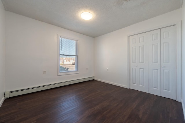 unfurnished bedroom featuring a baseboard radiator, a textured ceiling, dark hardwood / wood-style flooring, and a closet