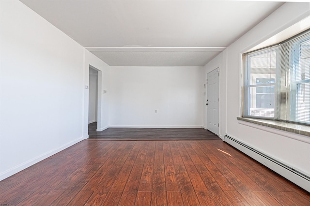 spare room featuring baseboard heating and dark wood-type flooring