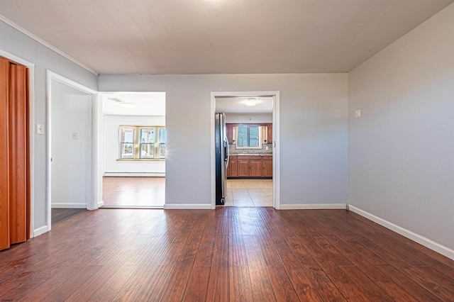 unfurnished room featuring baseboard heating and wood-type flooring