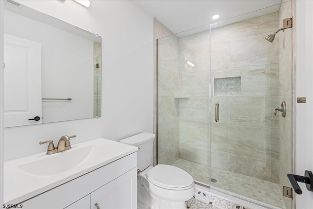 bathroom featuring vanity, a shower with door, and toilet