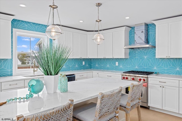 kitchen featuring white cabinets, decorative light fixtures, stainless steel stove, and wall chimney exhaust hood