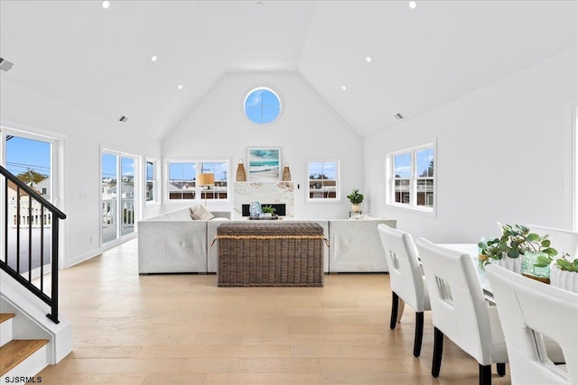 living room with high vaulted ceiling and light hardwood / wood-style flooring