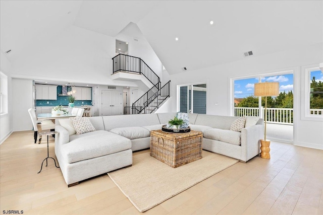 living room featuring high vaulted ceiling and light wood-type flooring