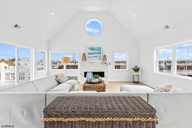 carpeted living room featuring a high end fireplace and high vaulted ceiling