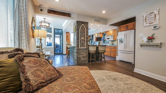 bedroom with white refrigerator with ice dispenser, a notable chandelier, and dark hardwood / wood-style flooring