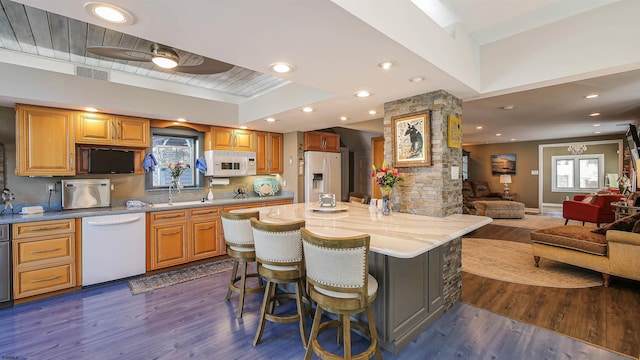 kitchen featuring white appliances, a breakfast bar, a center island, and dark hardwood / wood-style flooring