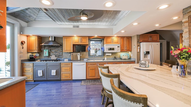 kitchen with dark wood-type flooring, wooden ceiling, white appliances, wall chimney range hood, and backsplash