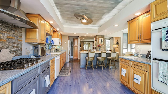 kitchen featuring appliances with stainless steel finishes, a breakfast bar, wall chimney range hood, and sink