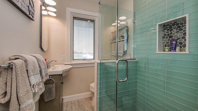 bathroom featuring a shower with door, vanity, hardwood / wood-style flooring, and toilet