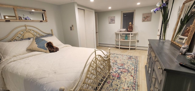 bedroom featuring baseboard heating, light wood-type flooring, and a closet