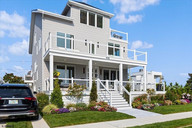 view of front facade with a balcony, covered porch, and a front yard