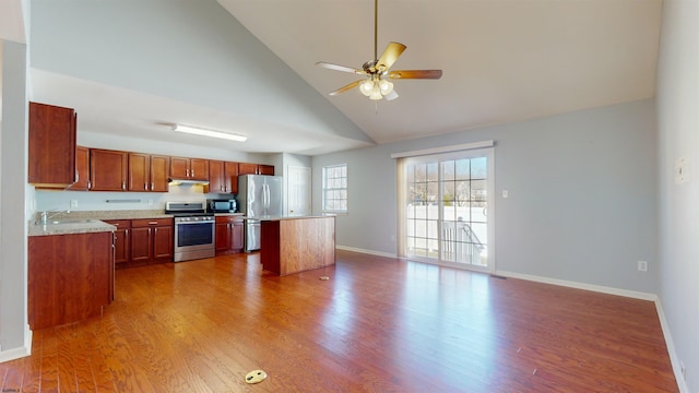 kitchen with sink, wood-type flooring, a kitchen island, ceiling fan, and stainless steel appliances