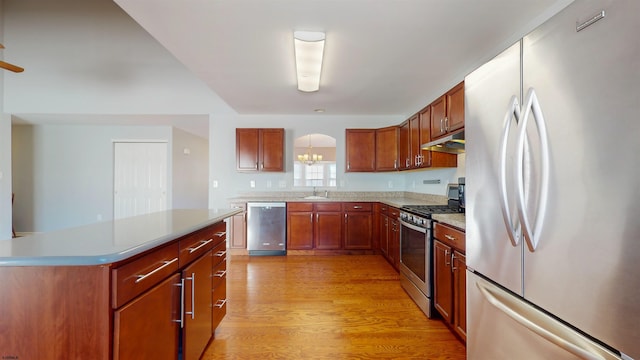 kitchen with a kitchen island, appliances with stainless steel finishes, sink, light hardwood / wood-style floors, and an inviting chandelier