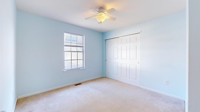 unfurnished bedroom featuring light carpet, a closet, and ceiling fan