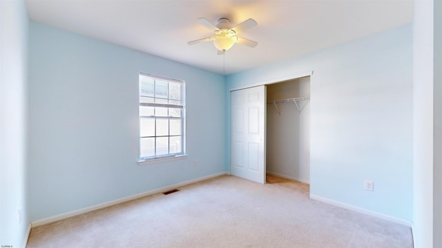 unfurnished bedroom featuring light carpet, ceiling fan, and a closet