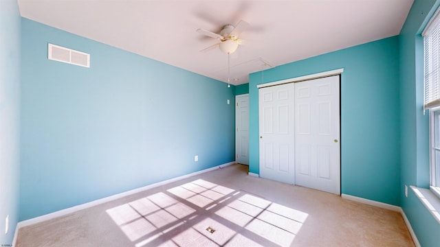 unfurnished bedroom featuring light colored carpet, a closet, and ceiling fan