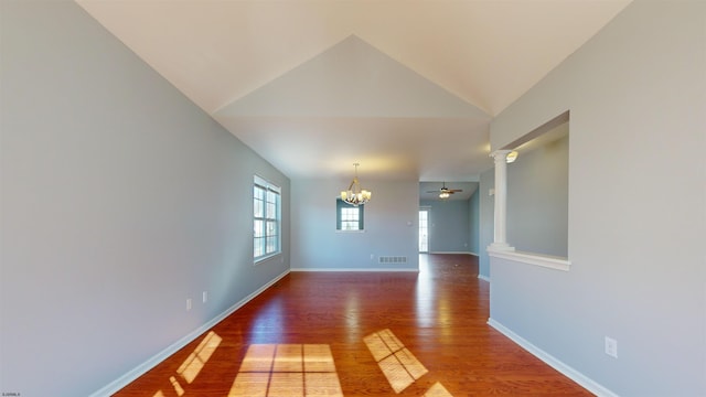 empty room with hardwood / wood-style flooring, lofted ceiling, ceiling fan with notable chandelier, and decorative columns