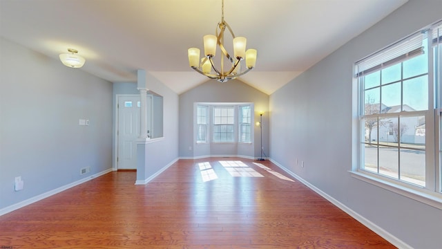 unfurnished dining area with lofted ceiling, hardwood / wood-style floors, and an inviting chandelier