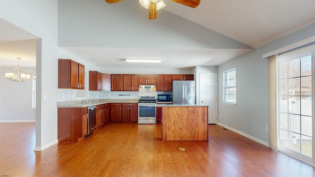 kitchen with appliances with stainless steel finishes, decorative light fixtures, sink, a center island, and light hardwood / wood-style flooring