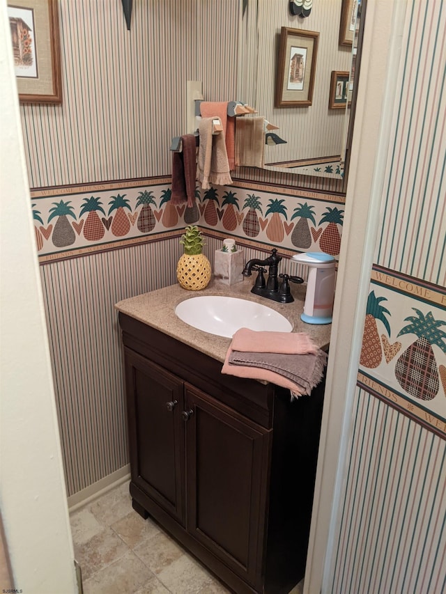 bathroom with tile patterned floors, wallpapered walls, vanity, and baseboards