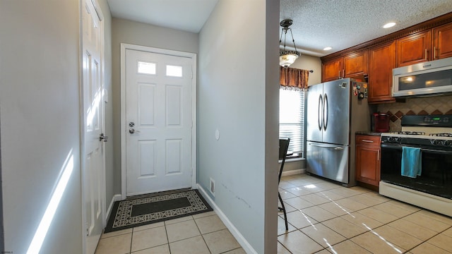 kitchen featuring light tile patterned flooring, hanging light fixtures, a textured ceiling, appliances with stainless steel finishes, and backsplash