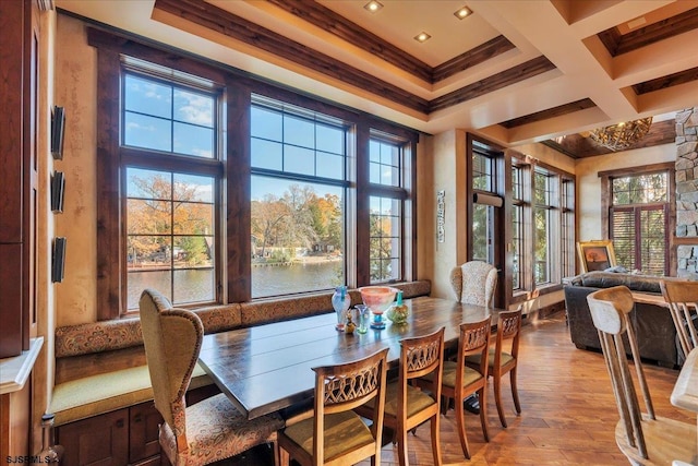 dining space featuring coffered ceiling, a water view, light hardwood / wood-style flooring, ornamental molding, and beam ceiling