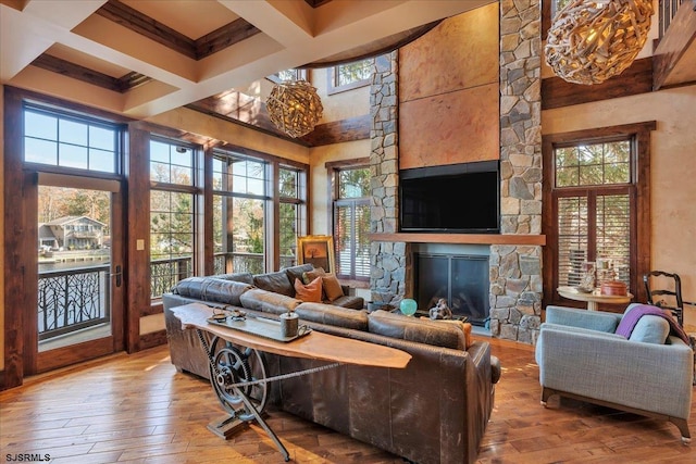 living room featuring hardwood / wood-style flooring, a high ceiling, coffered ceiling, a fireplace, and beamed ceiling