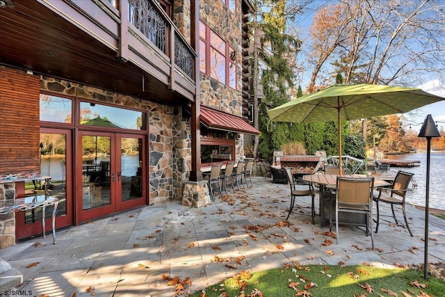 view of patio / terrace featuring a balcony, a water view, an outdoor bar, and french doors