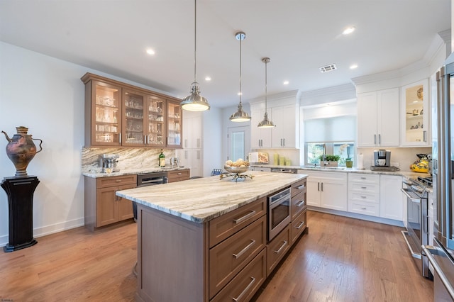 kitchen featuring white cabinetry, hanging light fixtures, decorative backsplash, and appliances with stainless steel finishes