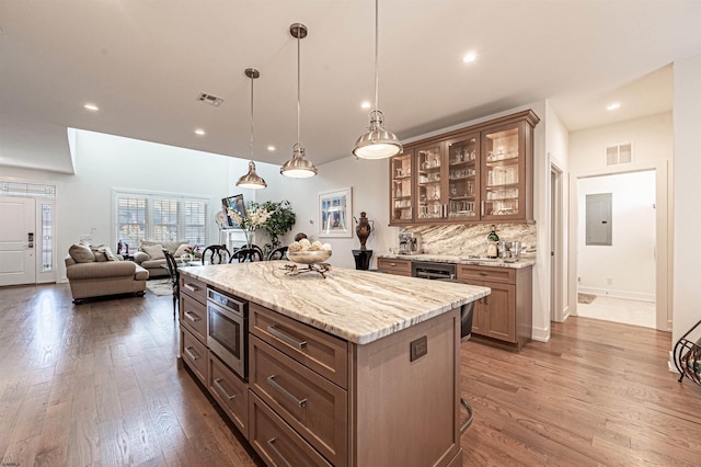 kitchen featuring tasteful backsplash, a center island, hanging light fixtures, stainless steel microwave, and a kitchen breakfast bar