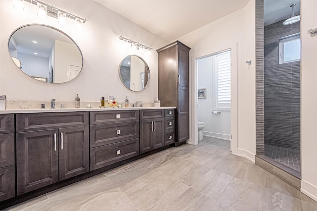 bathroom featuring vanity, toilet, and a tile shower