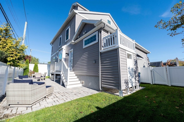 rear view of property featuring outdoor lounge area, a patio area, and a lawn