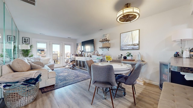 dining area featuring wine cooler, light hardwood / wood-style floors, and french doors