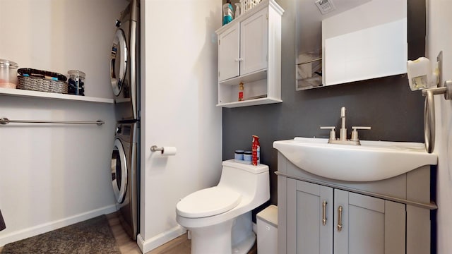 bathroom with vanity, toilet, and stacked washer / dryer