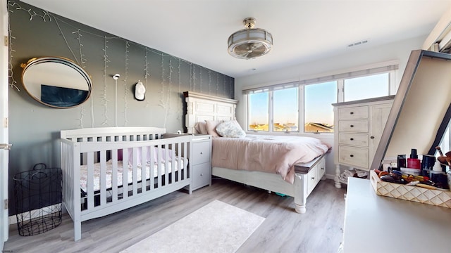 bedroom featuring hardwood / wood-style floors and a crib