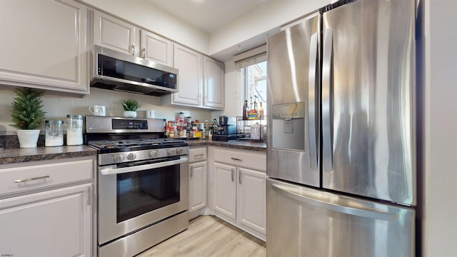 kitchen featuring appliances with stainless steel finishes, white cabinets, backsplash, and light hardwood / wood-style flooring