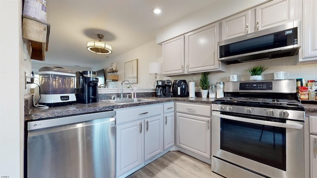 kitchen featuring stainless steel appliances, sink, white cabinets, and light wood-type flooring