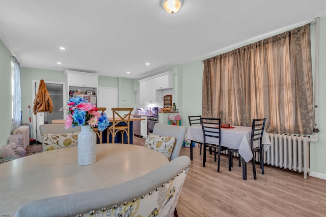 dining room with light hardwood / wood-style flooring and radiator heating unit