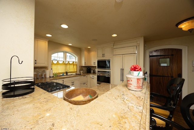 kitchen with light stone counters, built in appliances, sink, and a breakfast bar area