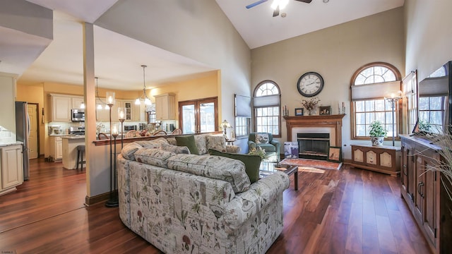 living room with a wealth of natural light, dark wood-type flooring, and high vaulted ceiling