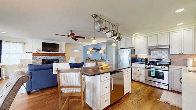 kitchen featuring tasteful backsplash, a center island, ornamental molding, stainless steel appliances, and white cabinets