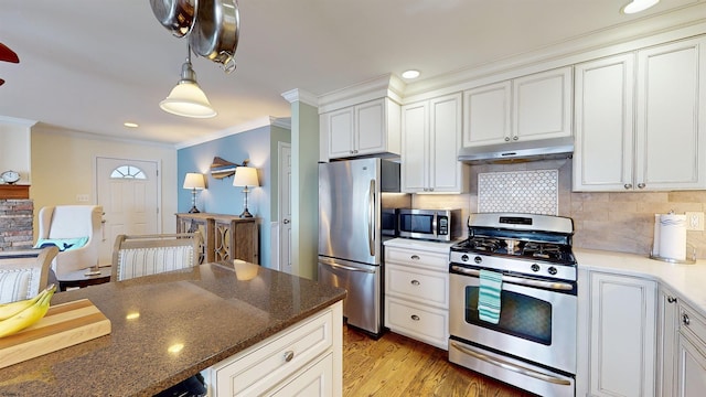 kitchen featuring tasteful backsplash, white cabinetry, stainless steel appliances, and dark stone countertops