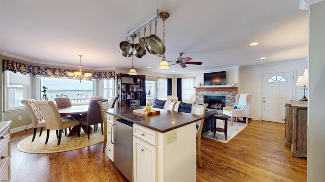 kitchen featuring crown molding, hanging light fixtures, fridge, a center island, and light wood-type flooring